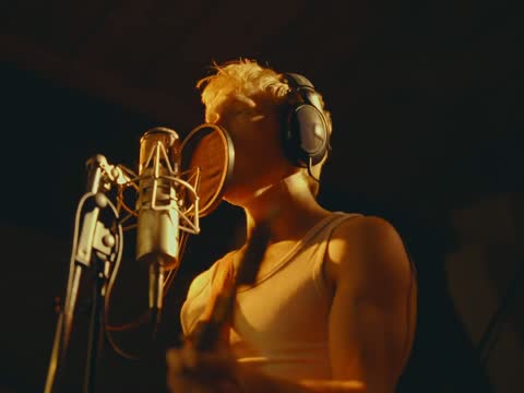RAW 002, frame 13: the singer at the microphone with the drum kit behind him