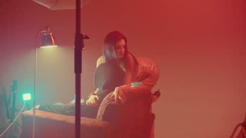 RUINAS BTS, frame 08: a woman seated in teal light on the red set