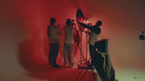 RUINAS BTS, frame 10: three crew members with a camera and light in red haze