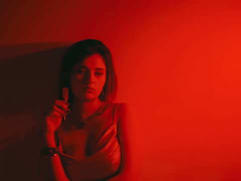 RUINAS, frame 09: a woman against a saturated red wall