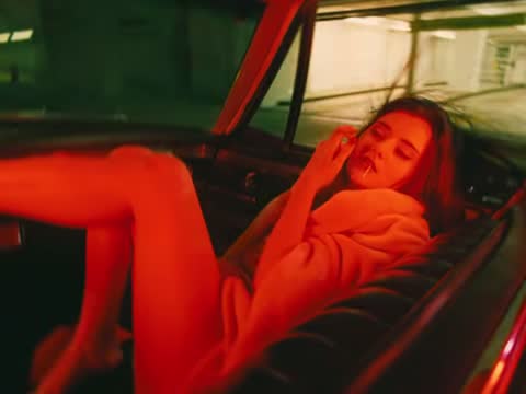 RUINAS, frame 12: a woman lying in the open trunk of a car at night