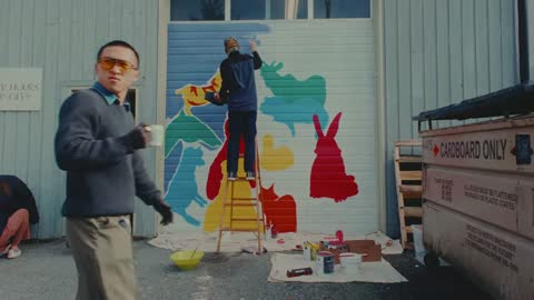 SPCA, frame 09: a man on a ladder and another standing as the mural takes shape