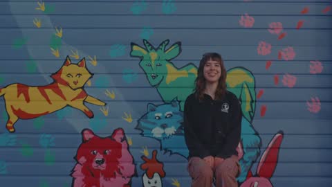 SPCA, frame 14: a woman standing in front of the finished mural